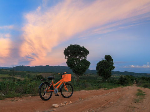 Bicycle On The Dirt Road At Sunset