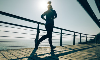 sporty young fitness woman running on coast