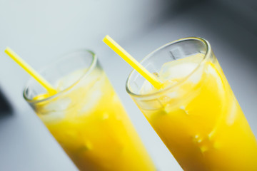 Glasses of orange juice with ice on a white background.