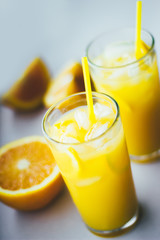 Glasses of fresh orange juice with ice and orange slices on a white background.