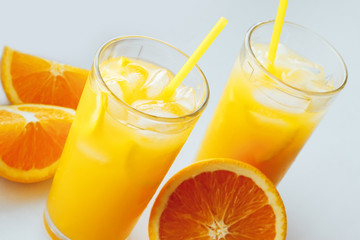 Glasses of fresh orange juice with ice and orange slices on a white background.