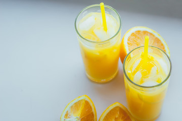 Glasses of fresh orange juice with ice and orange slices on a white background.