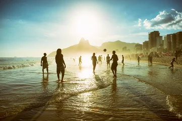 Poster de jardin Rio de Janeiro Silhouettes lointaines au coucher du soleil jouant au football de plage keepy-uppie sur le bord de la mer sur la plage d& 39 Ipanema Rio de Janeiro Brésil