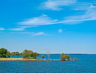 Landscape of a lake and blue sky. Bright view of Tawakoni Lake in Texas showing the surface of the water and the shore with green trees.