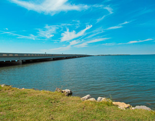 Sunny landscape of Tawakoni Lake in Texas. View from the shore showing the bridge, surface of water and blue sky with clouds.