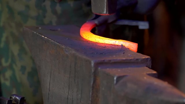 UHD closeup of a blacksmith forging the horseshoe with his hammer