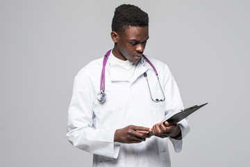 Friendly Afro-American doctor holding a clipboard and smiling at the camera isolated on gray background