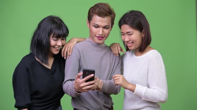 Three happy Asian friends using phone together