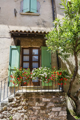 Fototapeta na wymiar Stone House with Balcony with Blooming Flowers .Cozy Italian Style Building Facade 