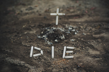 ashtray with ash and cigarette look like grave and cross