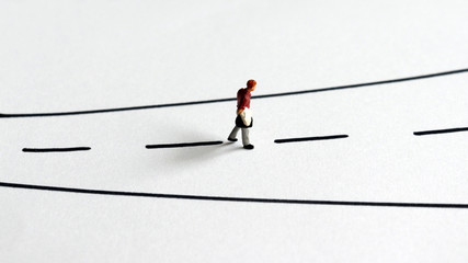 A miniature man walking alone on the street.