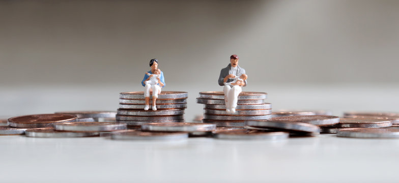 A&nbsp;miniature&nbsp;man&nbsp;and&nbsp;a&nbsp;miniature&nbsp;woman&nbsp;sitting&nbsp;with&nbsp;a&nbsp;baby&nbsp;on&nbsp;top&nbsp;of&nbsp;a&nbsp;stack&nbsp;of&nbsp;coins.