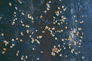 Black sesame seeds and cane sugar on dark concrete background. Food background. Copy space