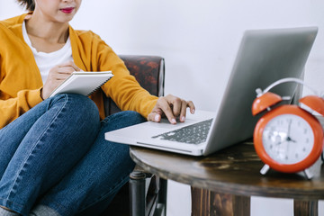Happy casual young asian woman working in home or small office with using a laptop and document report on desk as a freelancer