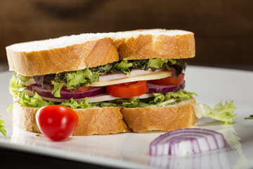 Sandwich with cheese, pork salami and vegetables on plate