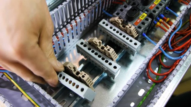 man fixes plastic support parts on switch board