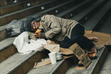 Naklejka na ściany i meble Potrait of homeless people sleeping with help paper sign