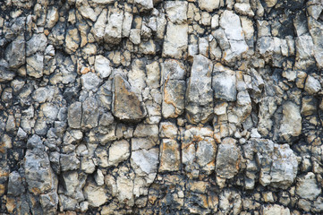 Pebble stones in a rocky wall. Natural background of a rocky stone wall