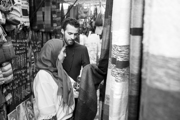 Smiling young muslim couple shopping carpets in a textile store