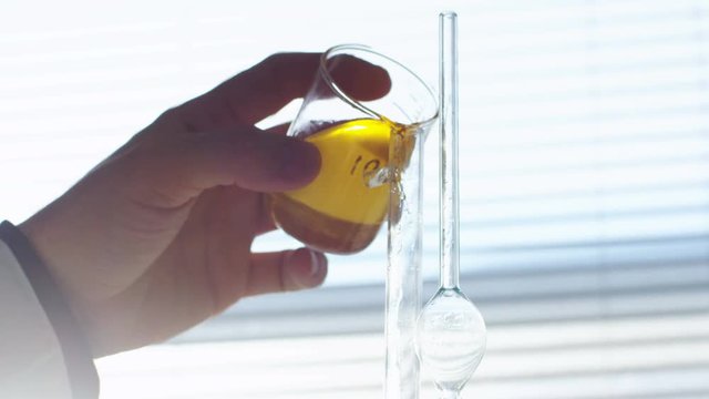 man pours tested distilled liquid into lab tube