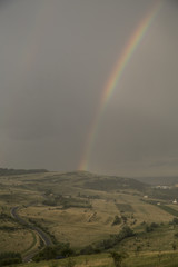 Beautiful rainbow over hills over the town and green hills