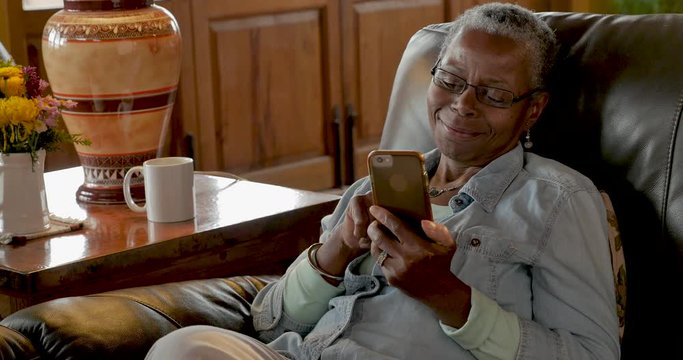 Happy smiling older black woman browsing and scrolling on her mobile phone