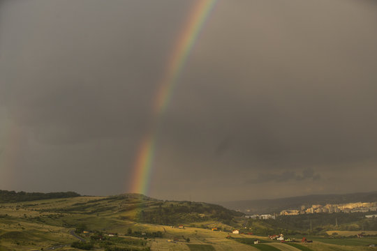 Beautiful rainbow over hills over the town and green hills © sandor69kv