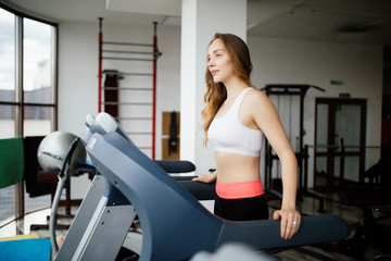 Fototapeta premium Young beauty woman working out on run simulator in sport gym club.