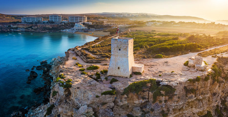 Fototapeta na wymiar Ghajn Tuffieha, Malta - Beautiful sunrise at Ghajn Tuffieha Watch Tower with Golden Bay beach at background
