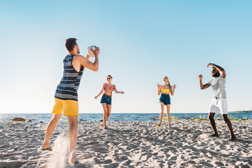 happy young multiethnic friends playing beach volleyball