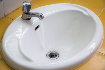 White wash sink in a bathroom with open the water