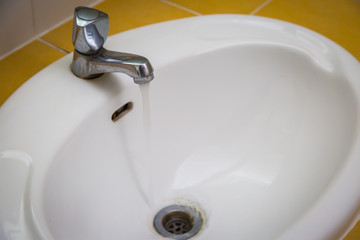 White wash sink in a bathroom with open the water