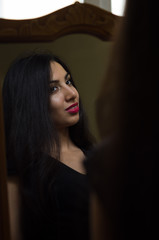 Fototapeta premium Young charming brunette girl looks at her reflection in the mirror