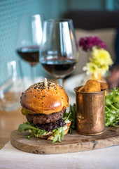 An american beef burger with fried potatoes and red wine