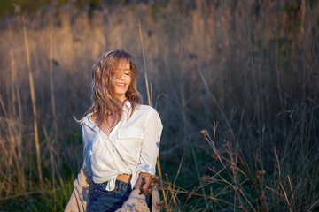 Cute charming girl in summer in the field. Young woman is happy and feels free outdoors