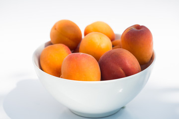 Apricots in a white bowl on white background