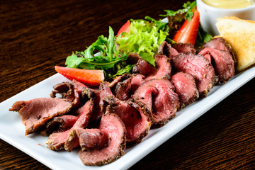 Juicy meat slices served with toasts and sauce in restaurant