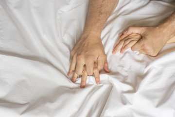 couple hands pulling white sheets in ecstasy, orgasm. Concept of passion. Oorgasm. Erotic moments. Intimate concept. Sex couple. Bedroom. Hotel room. Spa