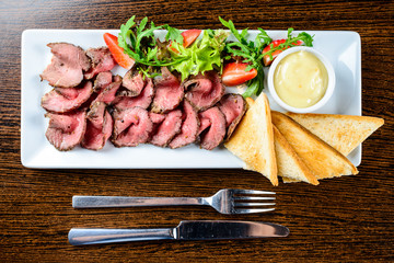 Juicy meat slices served with toasts and sauce in restaurant