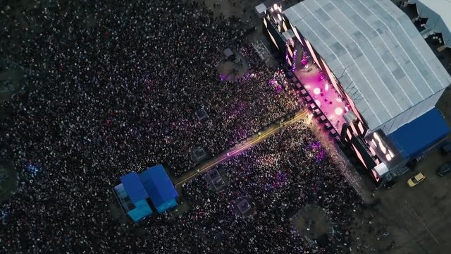 A large crowd of people at a music festival near the scene in the evening in the summer. Concert in the open air. Aerial view