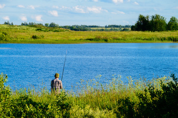 Obraz na płótnie Canvas Unidentified man fishing on the lake
