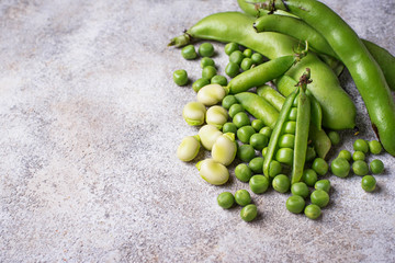 Fresh green peas and beans on light background