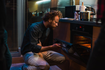 Guy opened the oven and looks whether the dish is ready