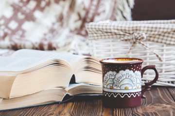 Details of still life in the home interior living room. Beautiful tea Cup, cut wood, books and pillows, candle on wooden background. Vintage, rustic. Cosy autumn-winter concept