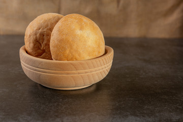 fresh buns with a crisp lie in a wooden bowl on a table on a stone background