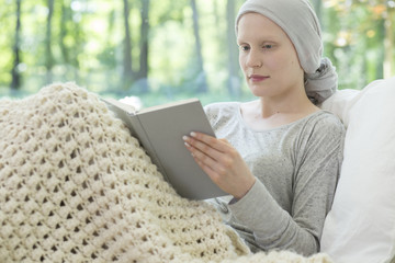 Sick woman with cancer reading book in the hospice