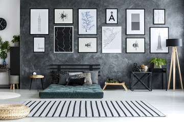 Striped carpet in spacious apartment interior with green futon against the wall with posters