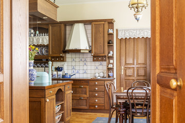 Chairs at dining table in classic wooden kitchen interior with island. Real photo