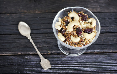 Cup of granola with cashews on a black wooden table. Top view. Traditional American Breakfast
