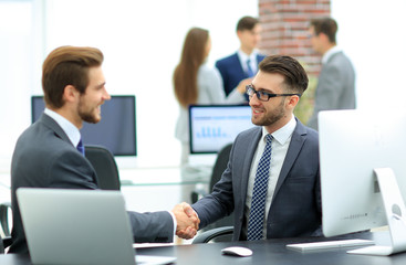 Successful managers shaking hands after closing deal in office